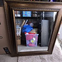 Large mirror with decorative bronze frame reflecting storage area behind