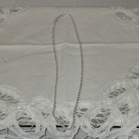 Full view of the silver rope chain necklace laid flat on cloth background showing chain detail and length