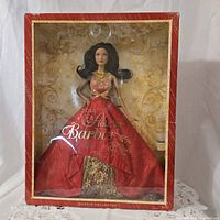 Front view of 2014 Holiday Barbie in original box, showing doll in red festive dress and gold accents.