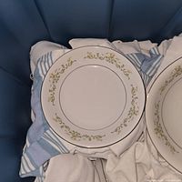 Porcelain dinner plate showing floral and gold scroll decoration around rim, white base color.