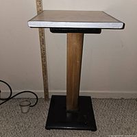 Photo of homemade pedestal table showing white square top, wooden single column, black square base, and a ruler measuring height.