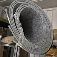 Roll of textured grey marine carpet, tightly rolled and secured with tape.