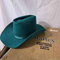 Front angled view of the green felt child's western hat resting on a cardboard box with Bailey Western Hats branding.