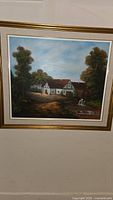 Full view of the framed painting showing a countryside scene with a house and trees.