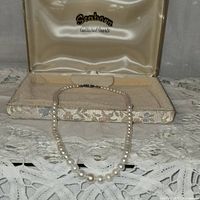 Full shot of vintage cultured pearl necklace in Seaborn case with satin interior and floral fabric lining on base.