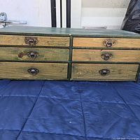 Front view of the vintage small wooden drawers with green frame and metal handles.