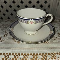 Side view of Wedgwood Waverly teacup on matching dessert plate showing pattern and gold trim.