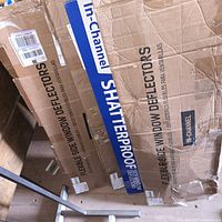 View of three cardboard boxes containing flexible side window deflectors for cars and SUVs, showing brand and product details including 'In-Channel' and 'Shatterproof' labels.