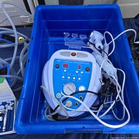 Plastic blue bin contains the dermabrasion machine with attached cords and handheld applicator visible, showing overall kit and condition.