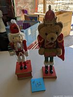 Photo of two nutcracker figurines on table, one traditional wooden soldier and one bear figure in royal attire.