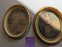 Two oval framed pictures showing a girl in a white dress and a boy with a dog.