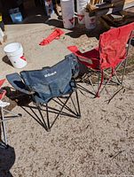 Two folding chairs, one blue RONA branded with cup holder and one red, seen from the side and front.
