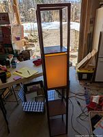 Three-shelf light wood shelving unit standing upright, showcasing the overall structure and middle light panel illuminated.