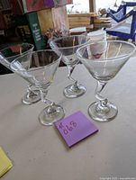 Four clear martini glasses arranged on a surface showing the angles and shape of the glasses.