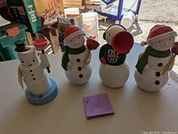 Four snowman cheerer figurines grouped together showing their different poses