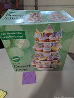 Box of Wilton 4-tier dessert tower showing assembled tower with cupcakes on the front.