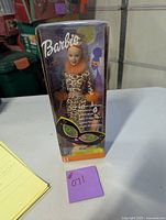 Front view of Barbie doll in leopard print outfit inside original box with clear plastic window.