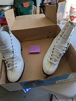 Pair of white figure skates inside original box, laced, clean, size 5.