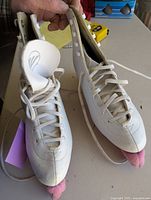 Front view of white ladies figure skates with laces and pink blade covers.