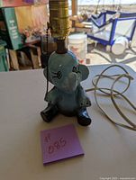 Full view of blue ceramic elephant lamp showing the body, head, and electric cord.