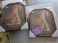 Two brand new 11x14 photo frames on a table with foam corner protectors and image insert showing a person wearing a red dress.