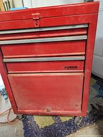 Red Waterloo roller tool box with visible drawers and storage compartments, exterior wear visible