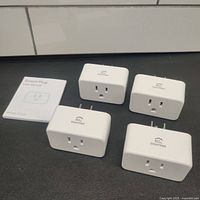 Four white EIGHTREE ET10 smart WiFi outlet plugs and user manual laid out on a dark surface.