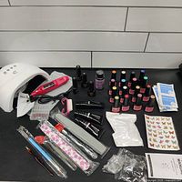 Full kit setup showing UV lamp, electric drill, gel polishes, nail files, brushes, nail tips, decals, and accessories