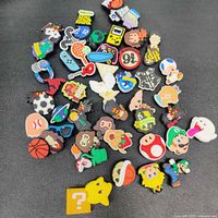 Overview of Crocs charms on black surface showing a variety of Nintendo, sports, and Harry Potter themed designs