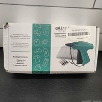Box showing packaging and contents description with image of the tagging gun and accessories.