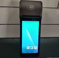 Front view of the handheld Android POS system showing touchscreen and contactless payment area above printer.