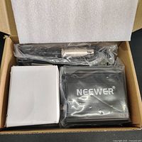 Packing box of NEEWER NW-100 phantom power supply including the unit, adapter box, and wrapped XLR cable.