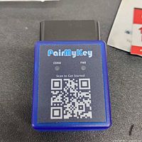 Front view of PairMyKey OBD II device with labels and QR code.