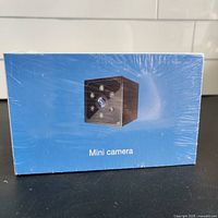 Front view of the sealed blue box showing image of the mini camera on the front, labeled 'Mini camera'.
