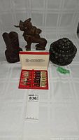 Full overview photo showing all items including cocktail forks in box, carved wood dragon, carved wood bust, and Tibetan Tsampa box
