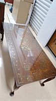 Full view of rectangular wood coffee table with brass inlay and glass cover on top