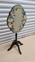 Full view of flip top table showing colorful floral tole painting, pedestal and tripod base