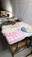Photo of assorted table linens spread out on table showing various folded pieces including lace edged and checkered patterns.