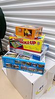 Photo showing the full lot stacked with visible box artwork and all puzzle boxes and roll-up