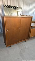 Front view of the three-door vintage laminate cabinet with metal handles, showing overall condition and style.