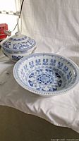 Two vintage ceramic bowls in blue and white patterns, one with lid and handles and one open serving bowl.