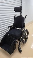 Front angled view of black wheelchair with seat cushion and headrest