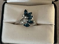 Close-up photo of a 14k white gold electroplate ring, size 11, featuring marquise blue stones and round clear stones.
