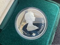 Obverse of silver coin showing Queen Elizabeth II with inscriptions 'ELIZABETH II CANADA 1987' and maple leaf, housed in green presentation box.