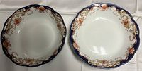 Two Bishop Stonier serving bowls with floral and dark blue patterned scalloped edges.