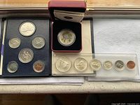 Top view of the three coin groups, showing the 1967 and 1982 coin sets in blue holders and the 2012 Grosbeak coin box with color bird design.