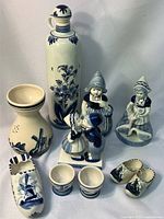 Full view of all ceramic items including bottle, vase, three figurines, two open containers, and ceramic shoes.