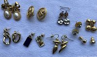 Top view of all nine earring pairs on white background showing style variety
