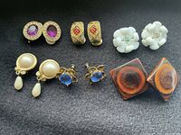 Six pairs of vintage clip and screw back earrings of various designs, colors, and materials.