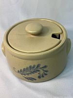 McCoy pottery crock with lid, beige with blue leaf decoration on side.